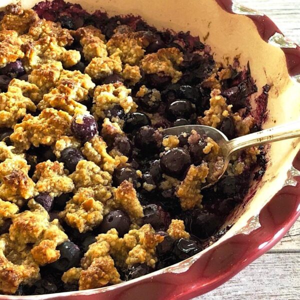 Blueberry crumble in a baking dish with a spoon.