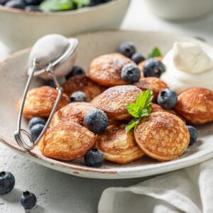 A plate of Dutch poffertjes made with blueberries.