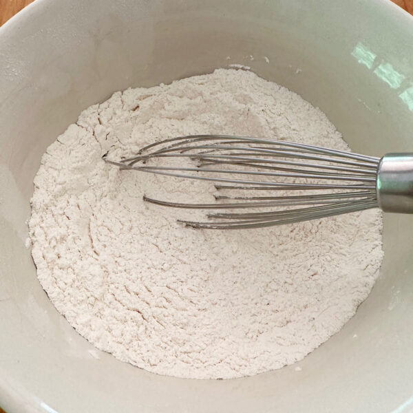 Dry ingredients for biscuits in a bowl with a whisk.