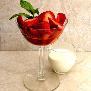 Fresh strawberries in parfait glass with a side of cream