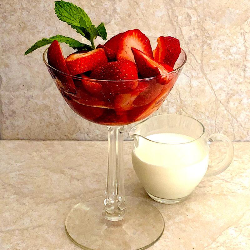 Fresh strawberries in parfait glass with a side of cream