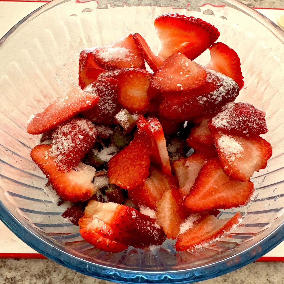 Strawberries and rhubarb macerating in a bowl with sugar.