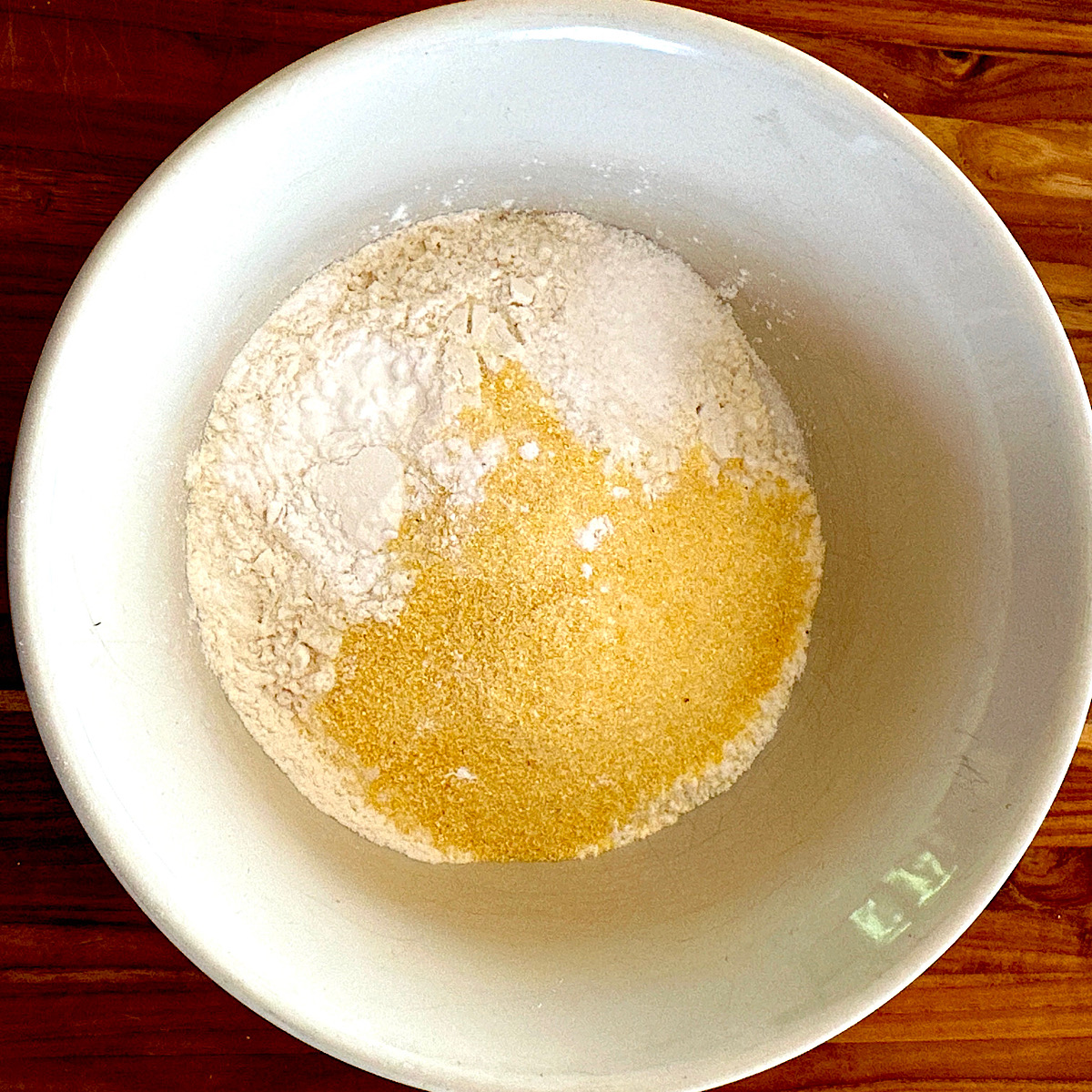 Flour, sugar, cornmeal and baking soda in bowl prepping for sheet cake.