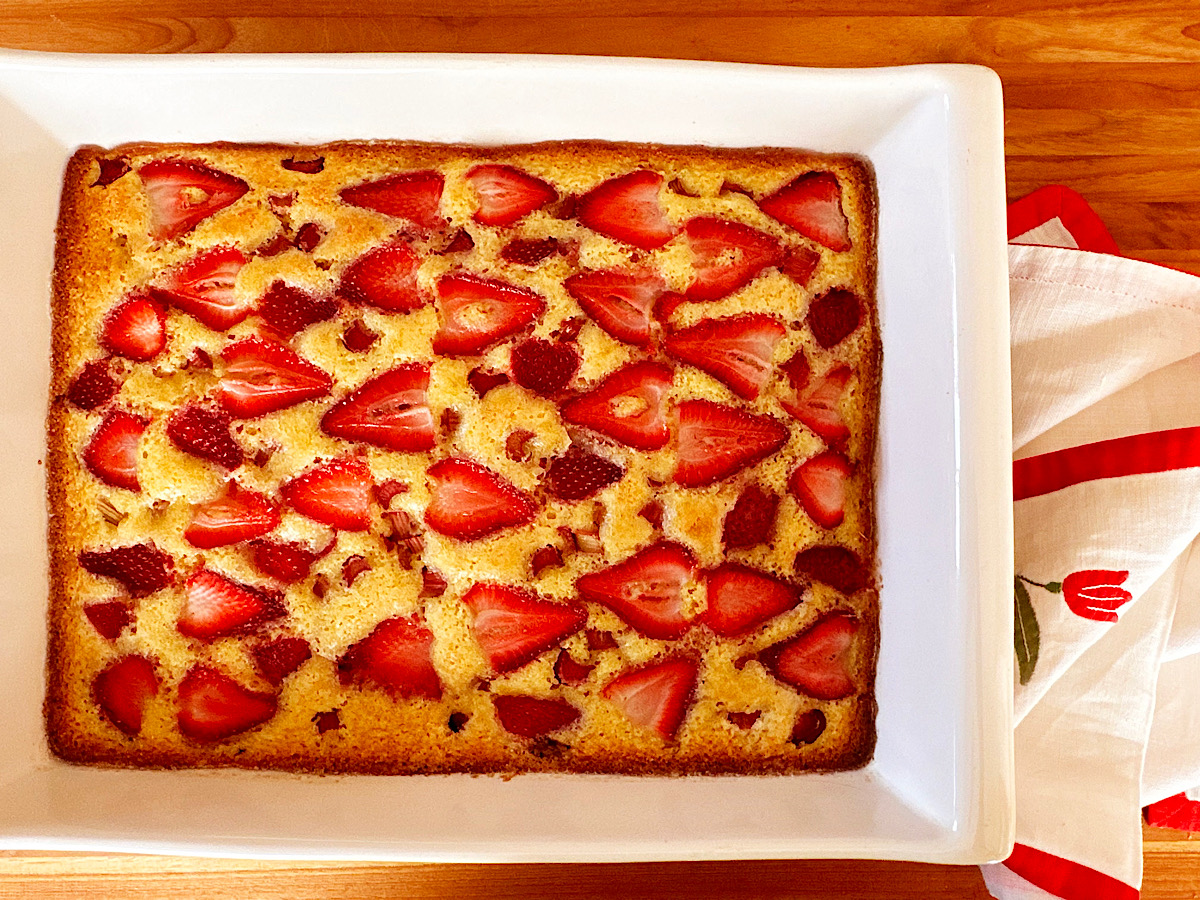 Strawberry rhubarb sheet cake in white baking dish.