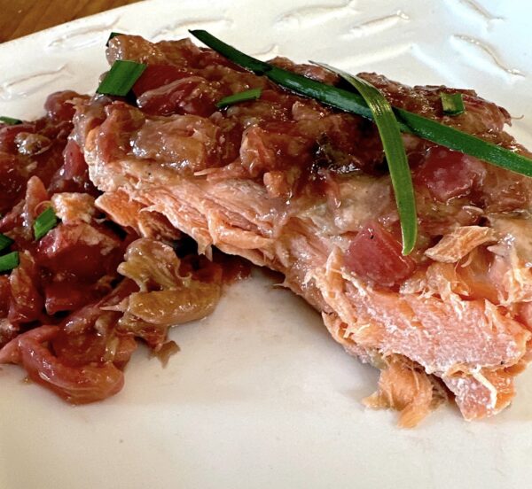 Roasted salmon with a rhubarb topping garnished with green onions.