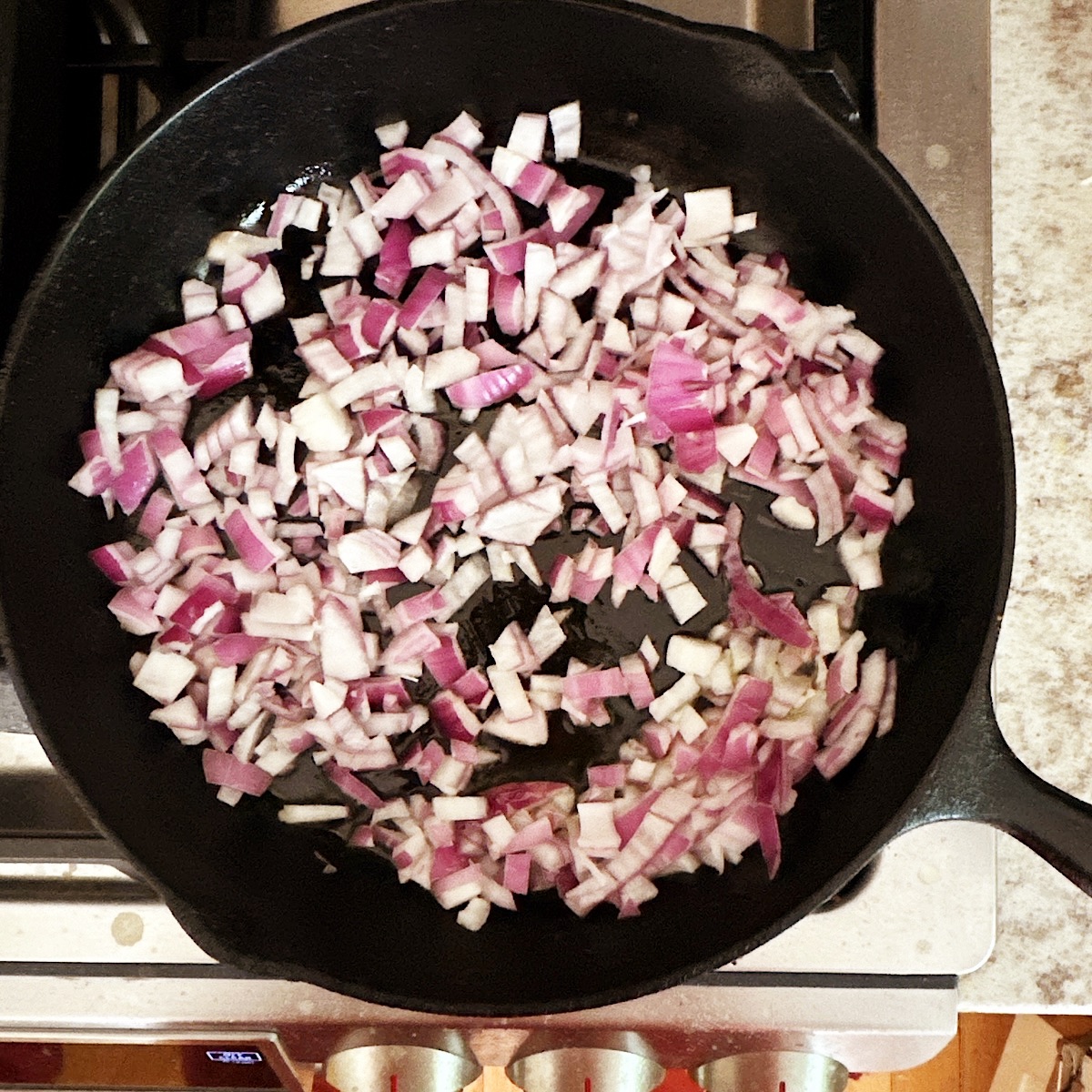 Chopped purple onion in cast iron skillet.