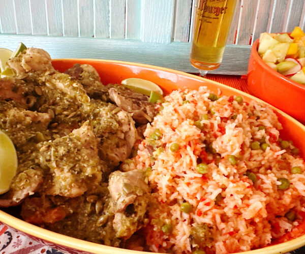 Chicken pipian with a side of Mexican rice in a large platter.