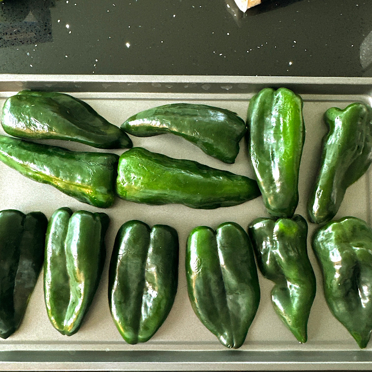 Poblano peppers laid out on a sheet pan.