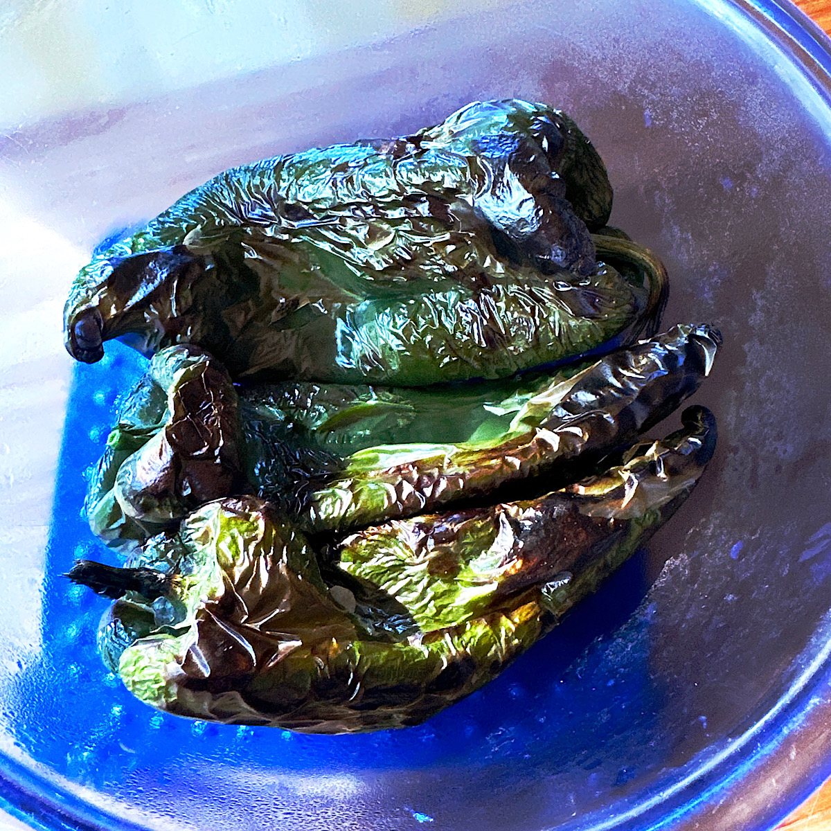 Blackened poblano peppers in a blue bowl.