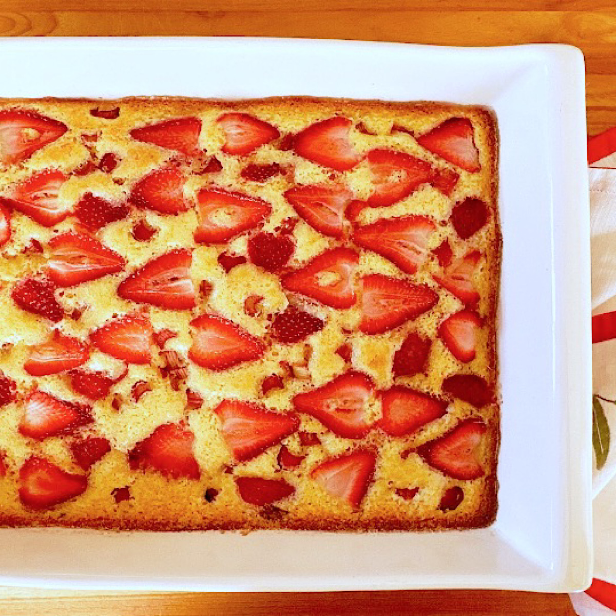 Strawberry rhubarb sheet cake in white baking dish.