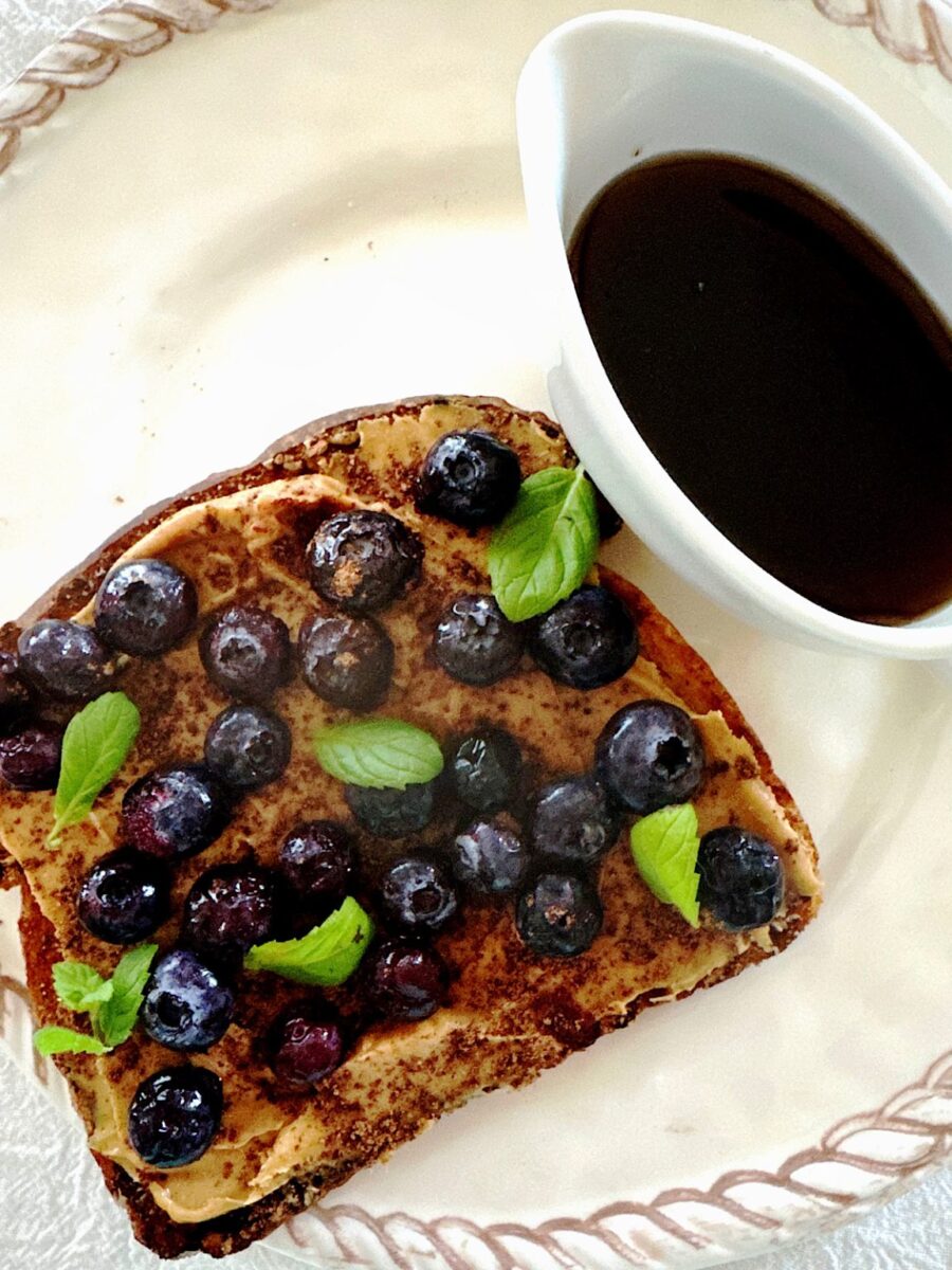 Blueberry toast with peanut butter, cocoa powder, mint leaves and maple syrup