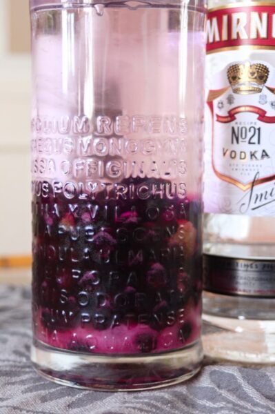 Bottle of blueberry infused vodka with bottle of vodka in background