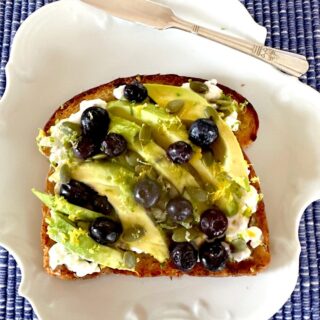 blueberry toast with avocados and cottage cheese on a white plate.