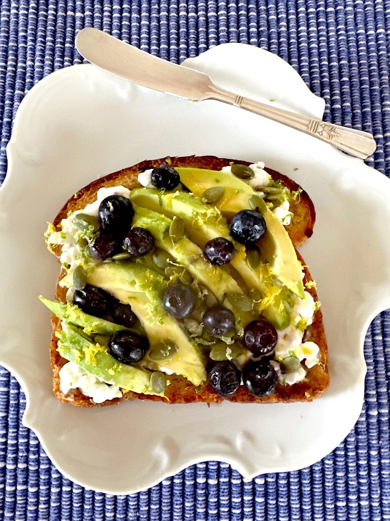 blueberry toast with avocados and cottage cheese on a white plate.