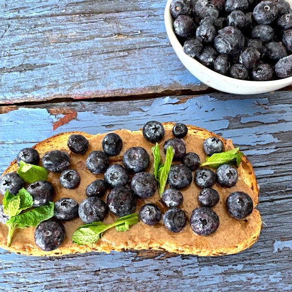 Blueberry toast with almond butter and mint leaves