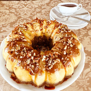 Chocoflan on a white platter with caramel sauce in background.