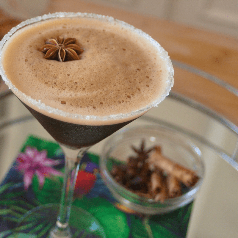 Chai espresso martini on flowered napkin with a side of spices.