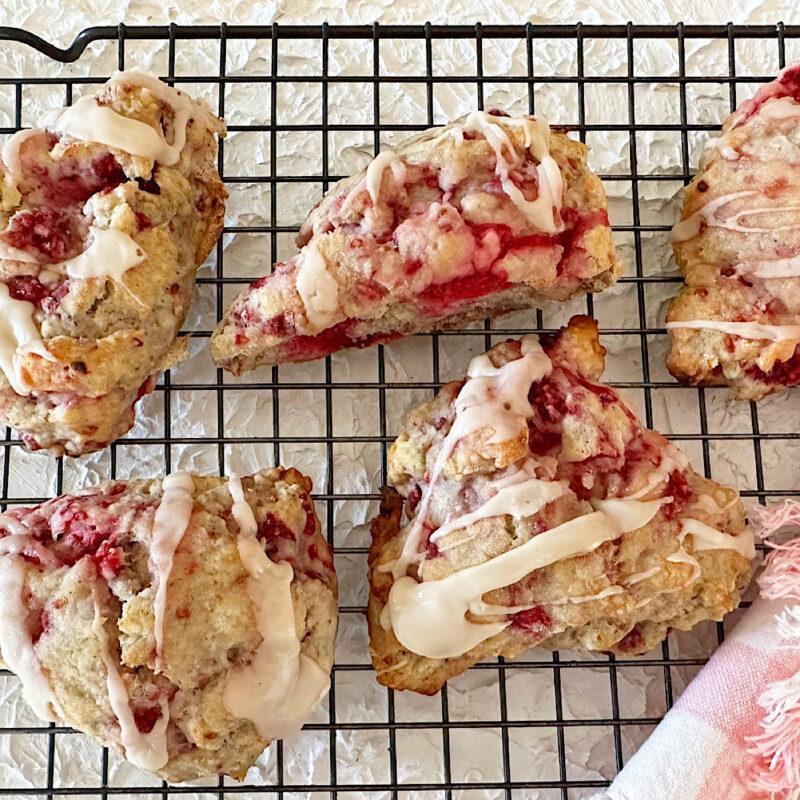 Raspberry scones with lemon vanilla icing on a baking rack