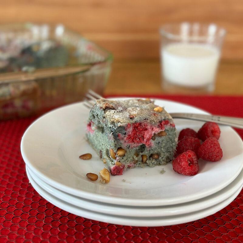 Blue corn masa and raspberry bar on white plates with milk in the background