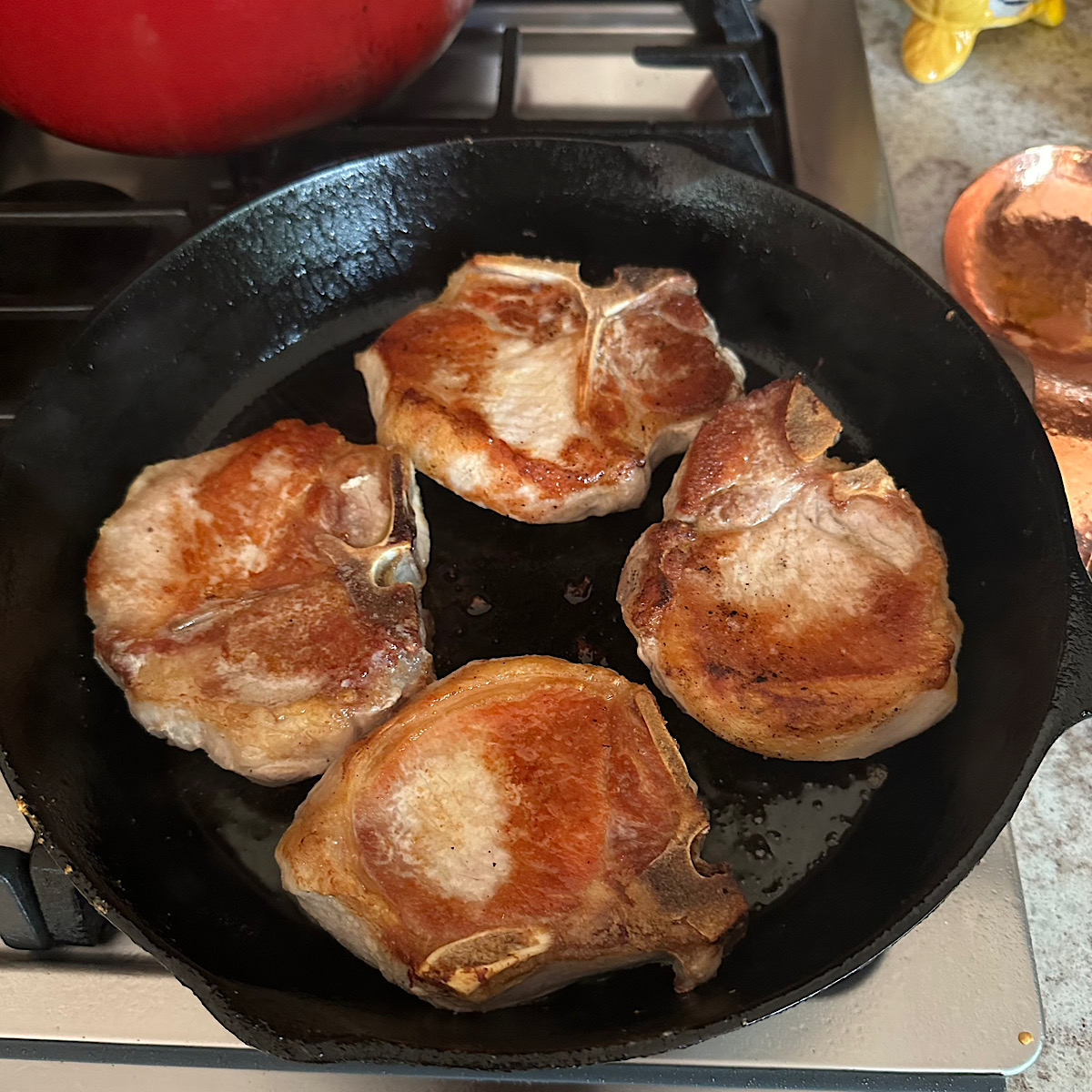 4 pork chops browning In a cast iron skillet