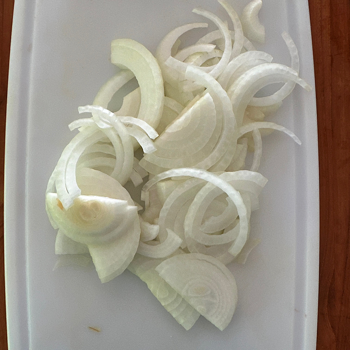 Sliced onions on a white cutting board.