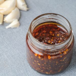 Mexican chile crisp in a small jar with garlic cloves.