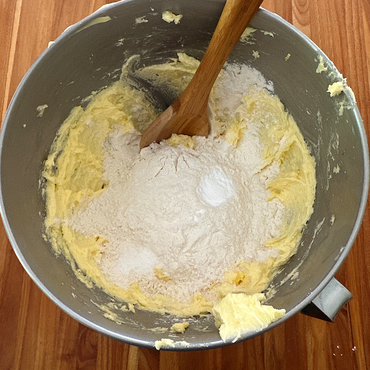 Adding flour and baking soda to wet ingredients for cookies.