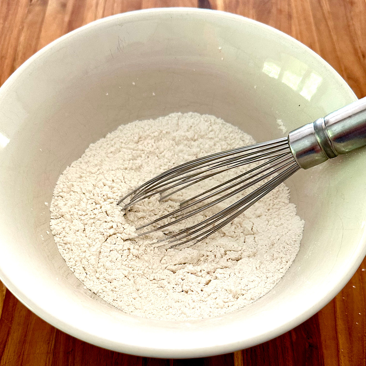 Flour, sugar and salt mixed in a bowl with a wire whisk.