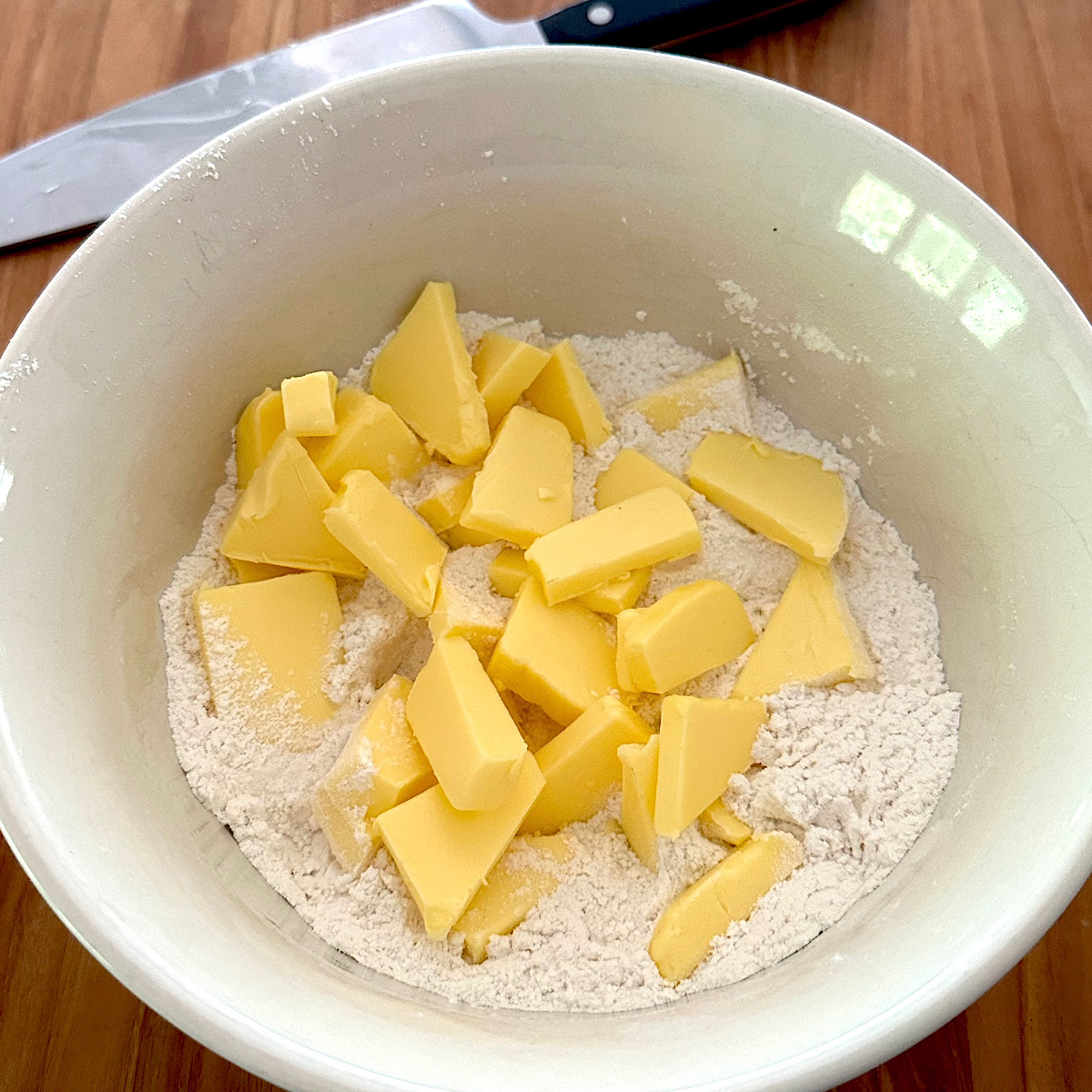 Cubes of butter added to flour and sugar in a bowl.