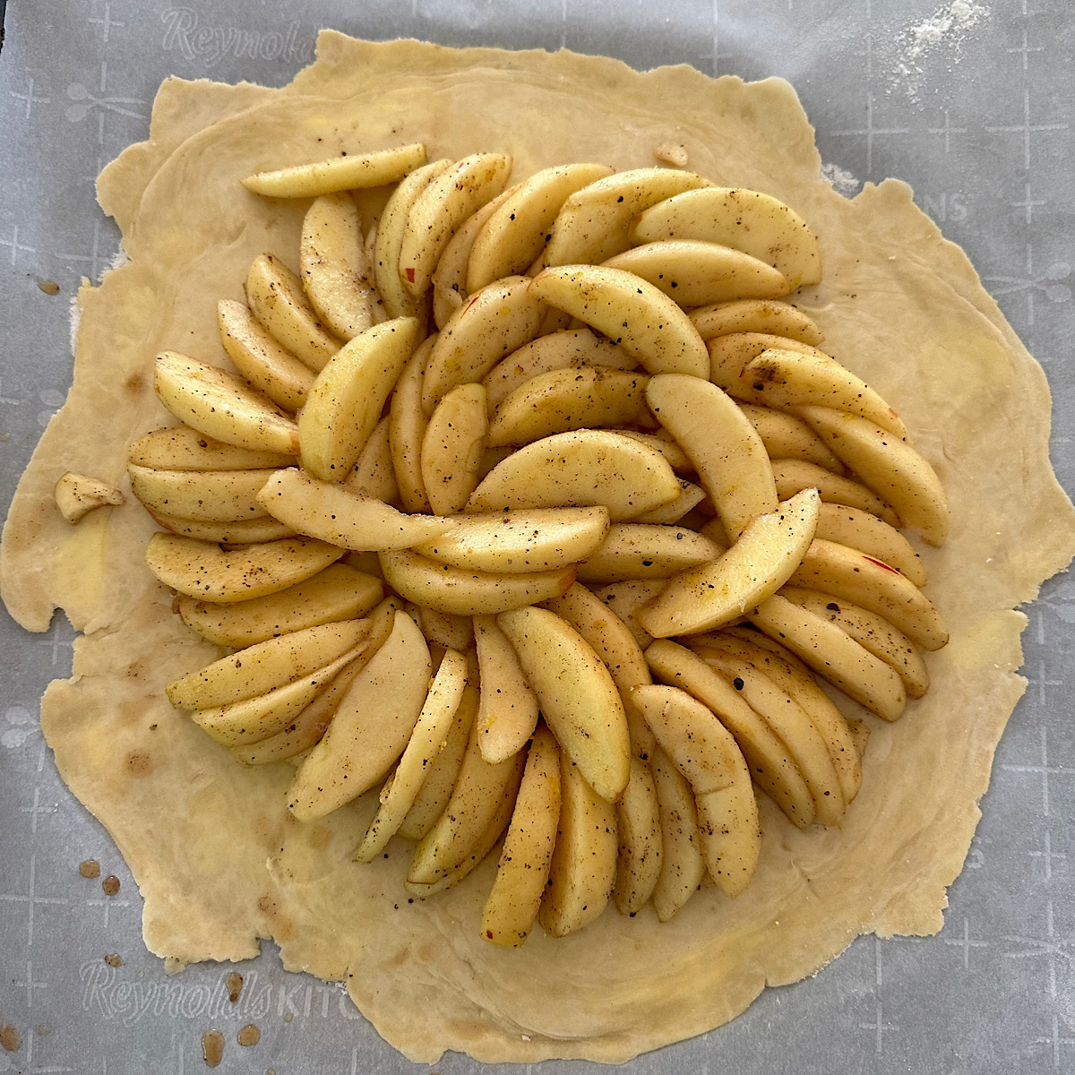 Spiced apple slices arranged on a round of dough.