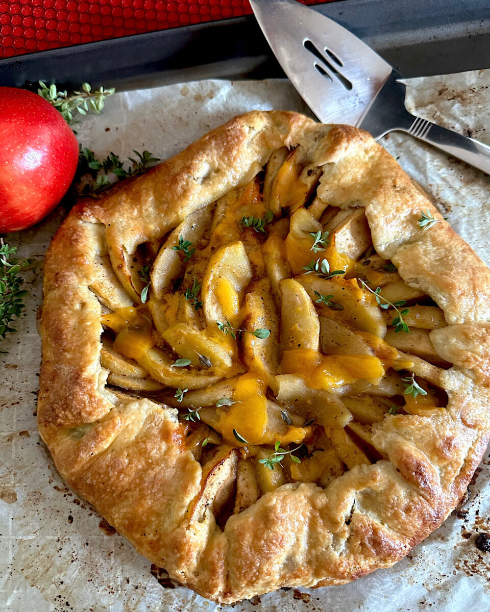 Apple cheddar galette n a sheet of parchment paper with a red apple.