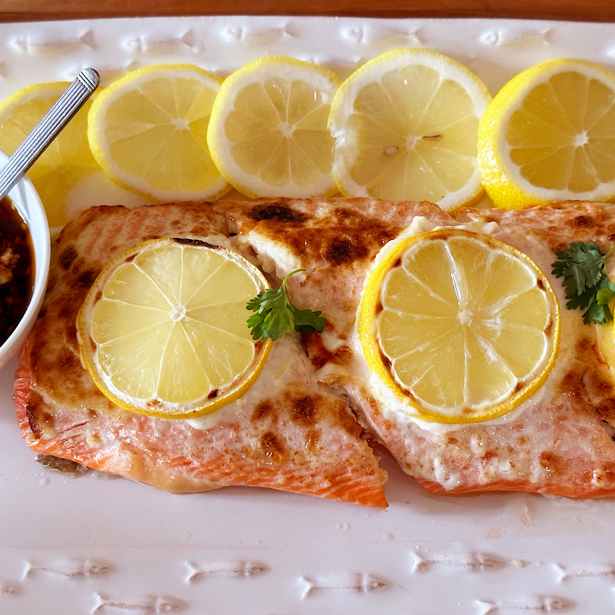 2 roasted salmon filets with mayonnaise and lemon slices on top.