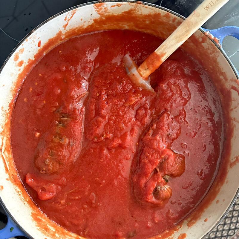 2 braciole simmering in rich tomato sauce.