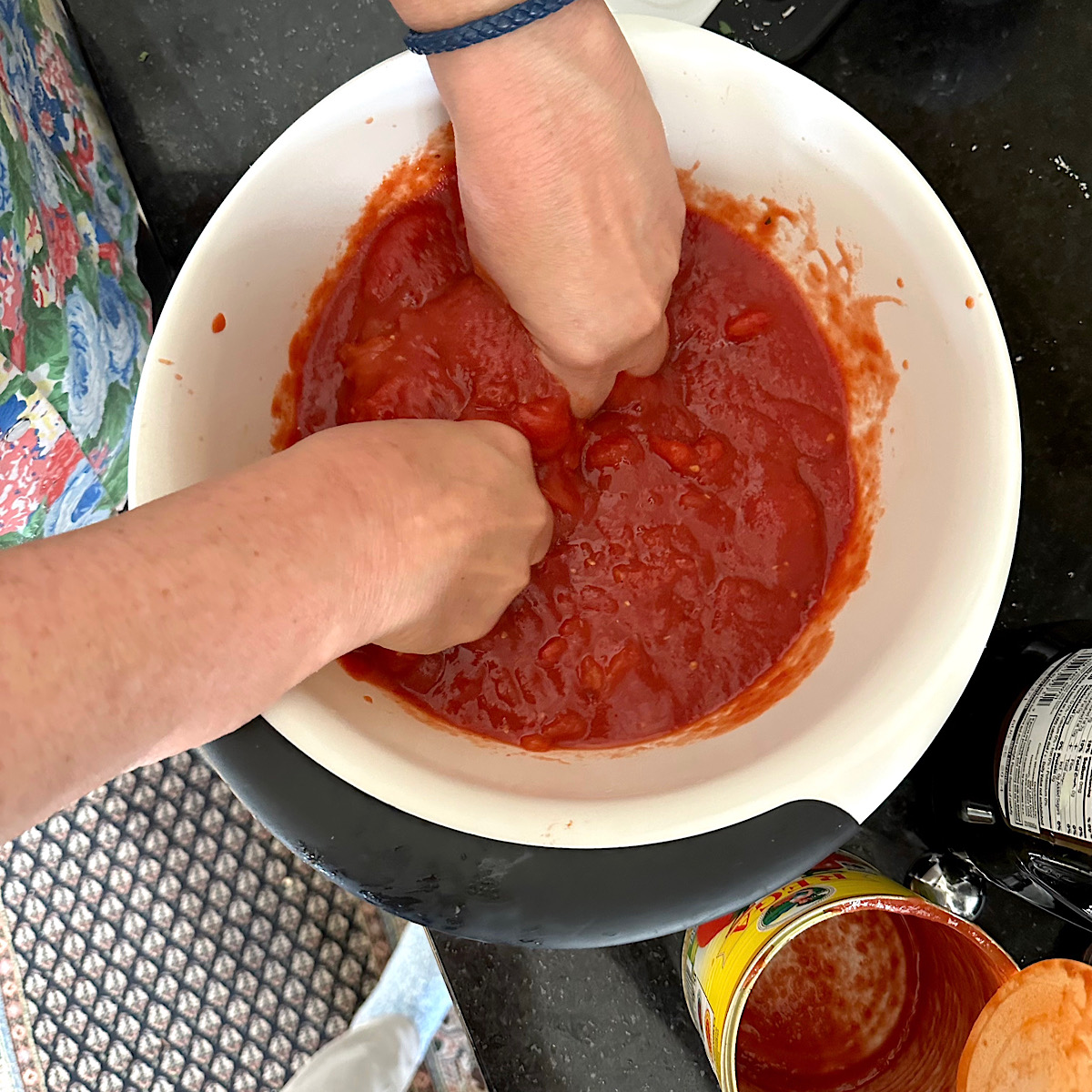 Squishing the San Marzano tomatoes with hands.