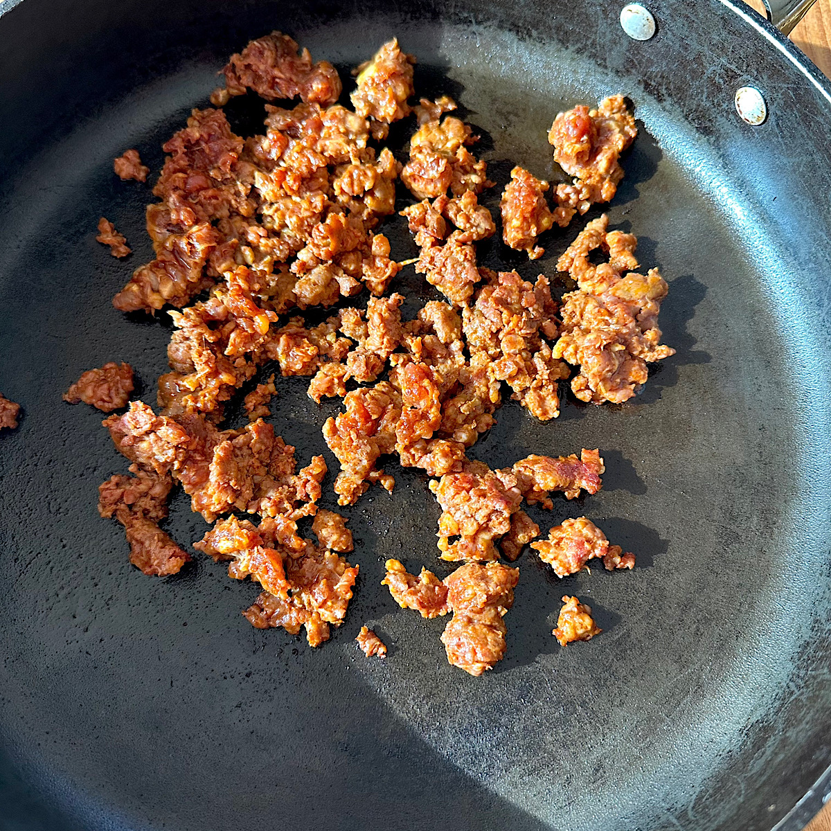 Ground chorizo cooking in a skillet.