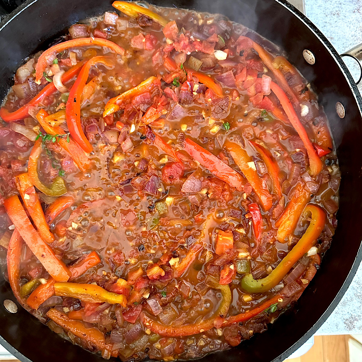 Skillet of onions and peppers cooking in sherry and herbs.
