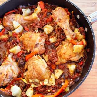 Finished skillet of chicken and chorizo stew with peppers and artichokes.
