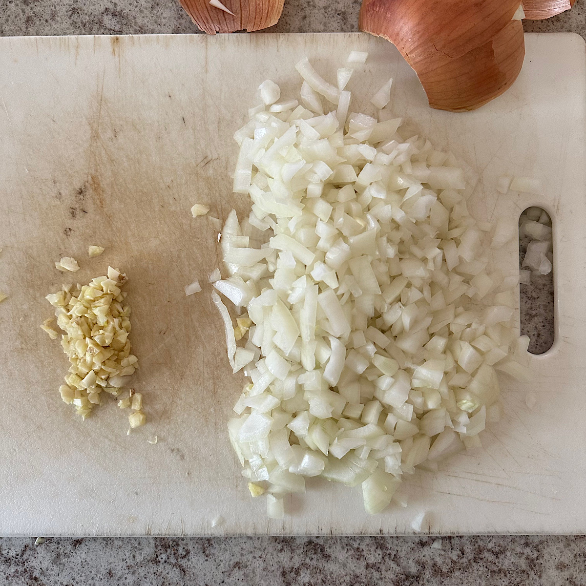 Chopped onion and garlic on cutting board.