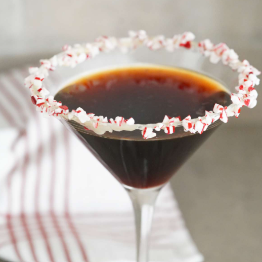 Photo of martini glass with dark brown espresso martini inside, rimmed in crushed candy canes.