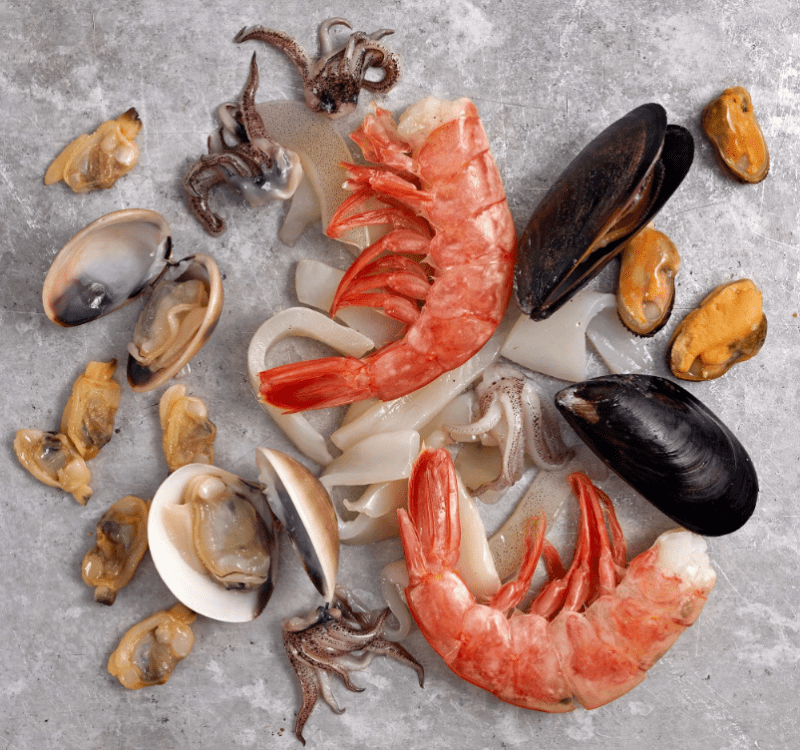 Photo of seafood for paella including jumbo shrimp, mussels, squid.