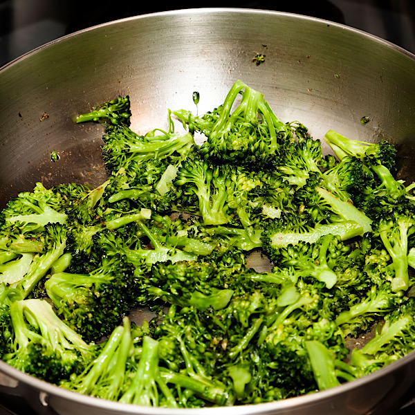 Broccoli cooking in a stainless steel pan.