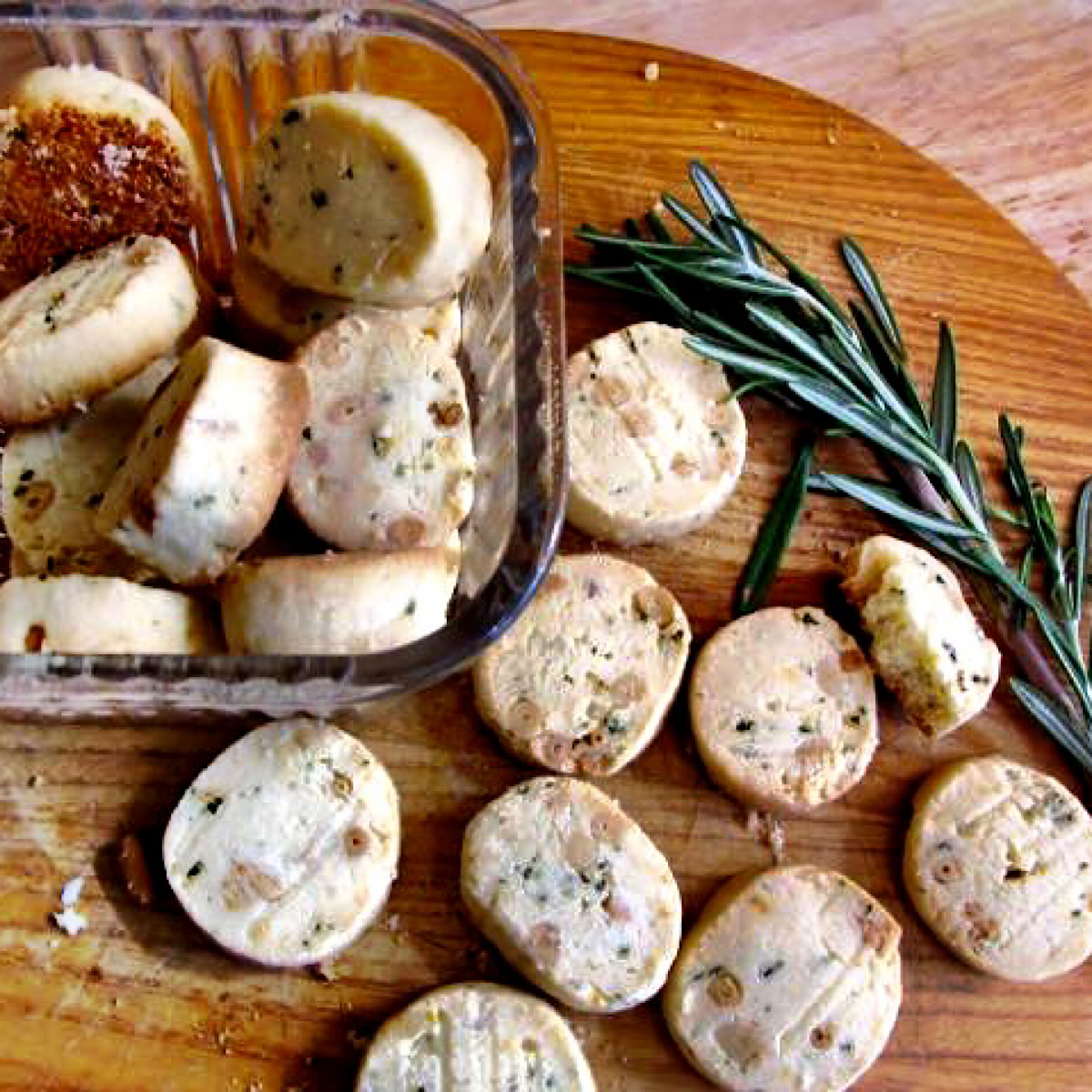 Rosemary sable cookies on a board with a sprig of rosemary for spring afternoon teas.