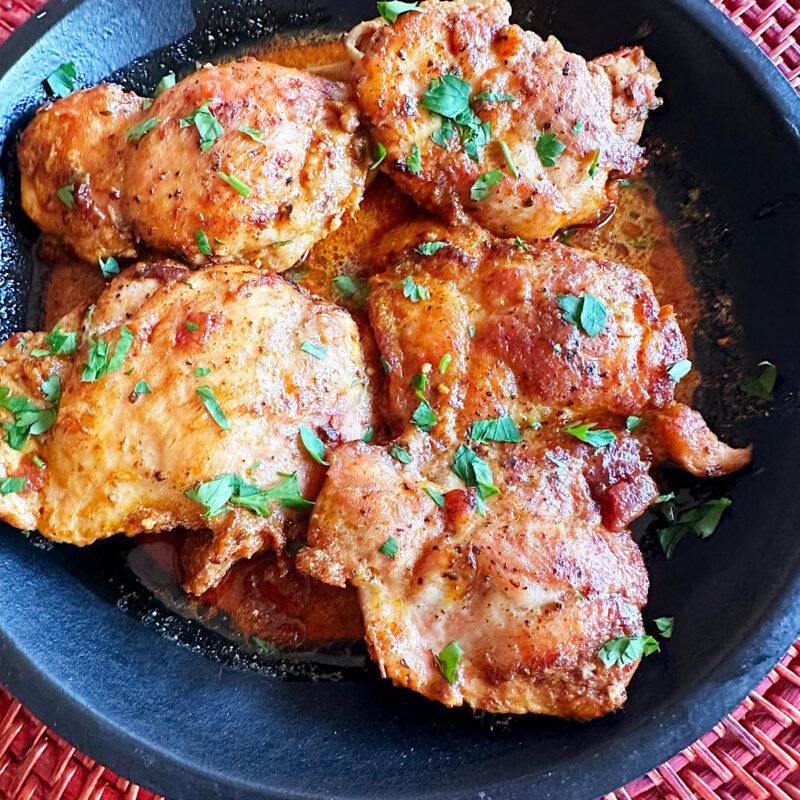 Chicken paprikash in a black bowl garnished with parsley