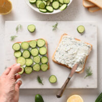 Ingredients for cucumber sandwiches laid out on cutting board.