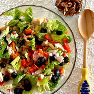 Bowl of chicken blueberry summer salad with side of walnuts