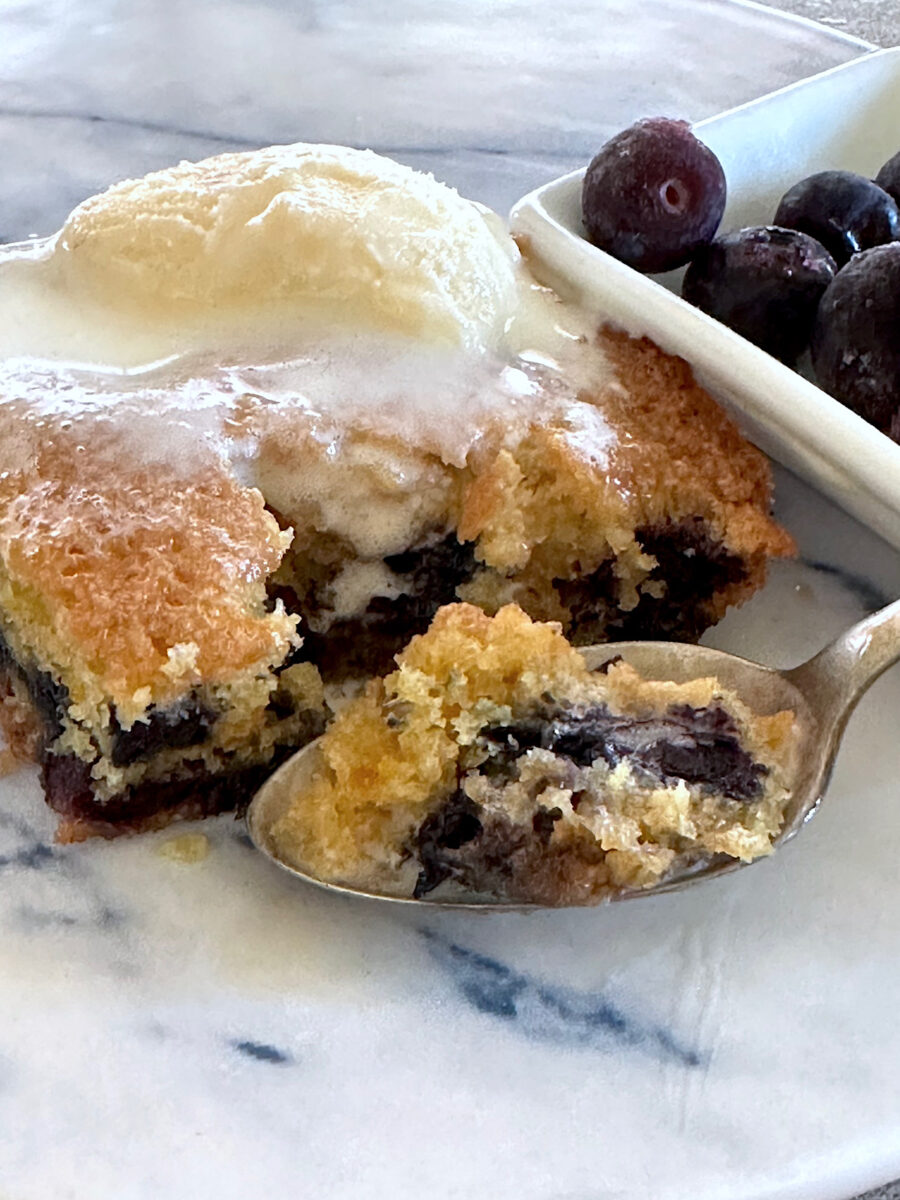 Blueberry cornmeal cake with ice cream and spoonful of cut cake.