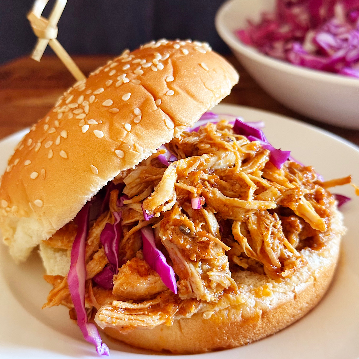 Shredded chicken BBQ sandwich on a bun with red cabbage.