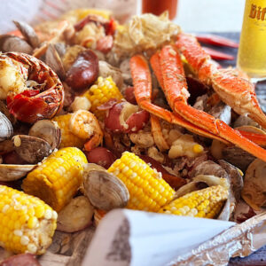 Seafood boil for a summer party, with corn, potatoes and a gkass if beer