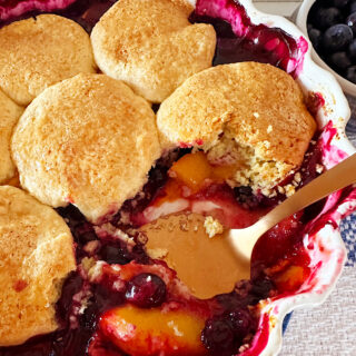 Southern cream biscuits on top of a peach and blueberry cobbler.