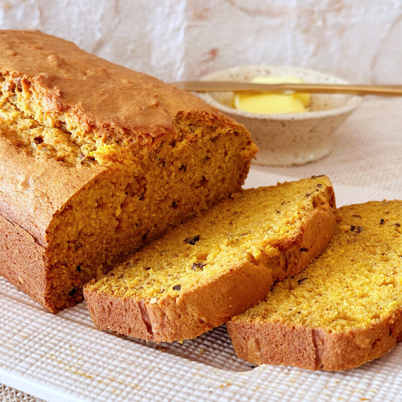 Pumpkin bread with bowl of butter in background.